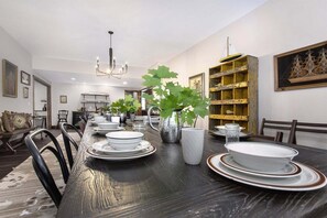 A dining room with a long table set for a meal, surrounded by chairs.