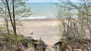 A beach with a wooden staircase leading to the shore, surrounded by trees and vegetation. - Pine Lodge: Lake Michigan Beach Access, Private Swimming Pool & Hot Tub, Sauna (Glenn)