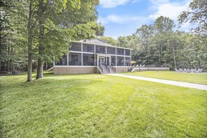 A modern building with a covered outdoor area, surrounded by a well-maintained lawn and trees.