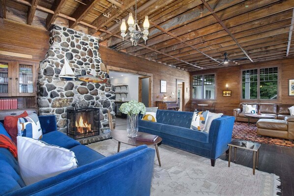 A rustic interior with a stone fireplace, wooden ceiling, and blue sofas.