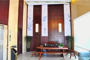 A room with a wooden door, a table with chairs, and two potted plants. - Linhai H Chain Lihao Star Hotel (Linhai)