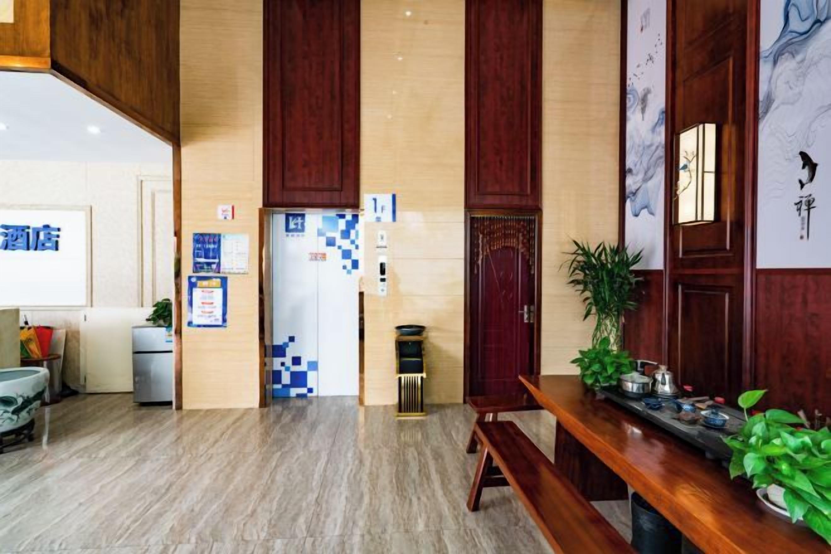Un hall d’hôtel comprenant un comptoir d’accueil, un espace salon et un mur orné d’un motif bleu et blanc.