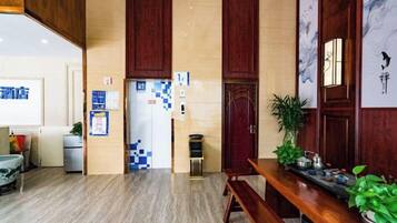 Un hall d’hôtel comprenant un comptoir d’accueil, un espace salon et un mur orné d’un motif bleu et blanc.