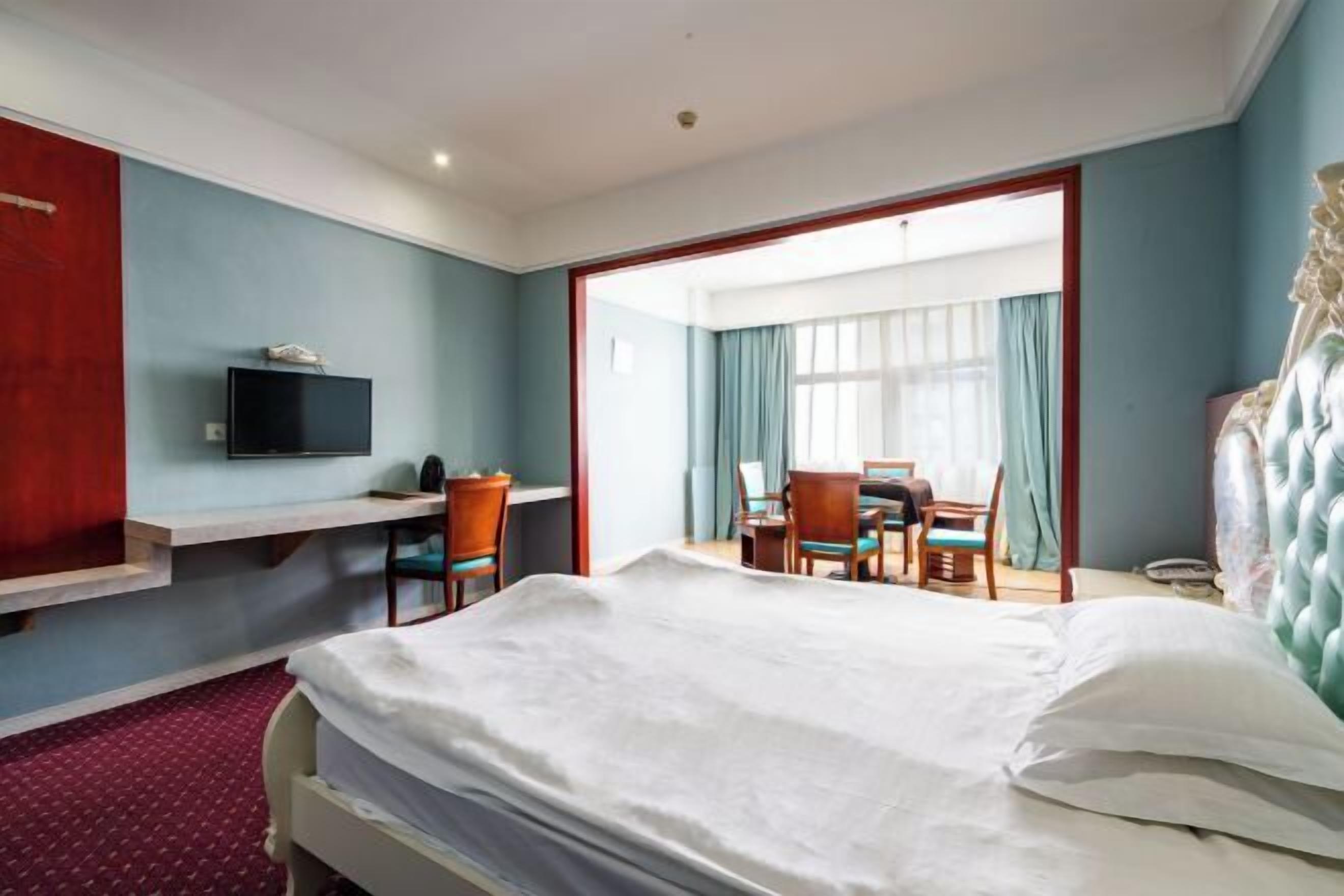 Una habitación de hotel con una cama, un escritorio, una silla, un televisor y un espejo grande.