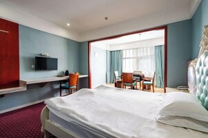 Una habitación de hotel con una cama, un escritorio, una silla, un televisor y un espejo grande.