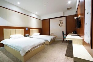 Habitación de hotel con dos camas, un escritorio y una silla.