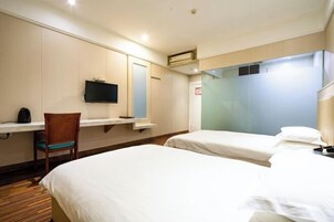 Habitación de hotel con dos camas, un escritorio, una silla, un televisor y un espejo.