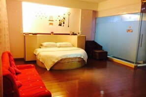 A bedroom with a bed, a red sofa, a wardrobe, and a wall with decorative elements. - Linhai H Chain Lihao Star Hotel (Linhai)