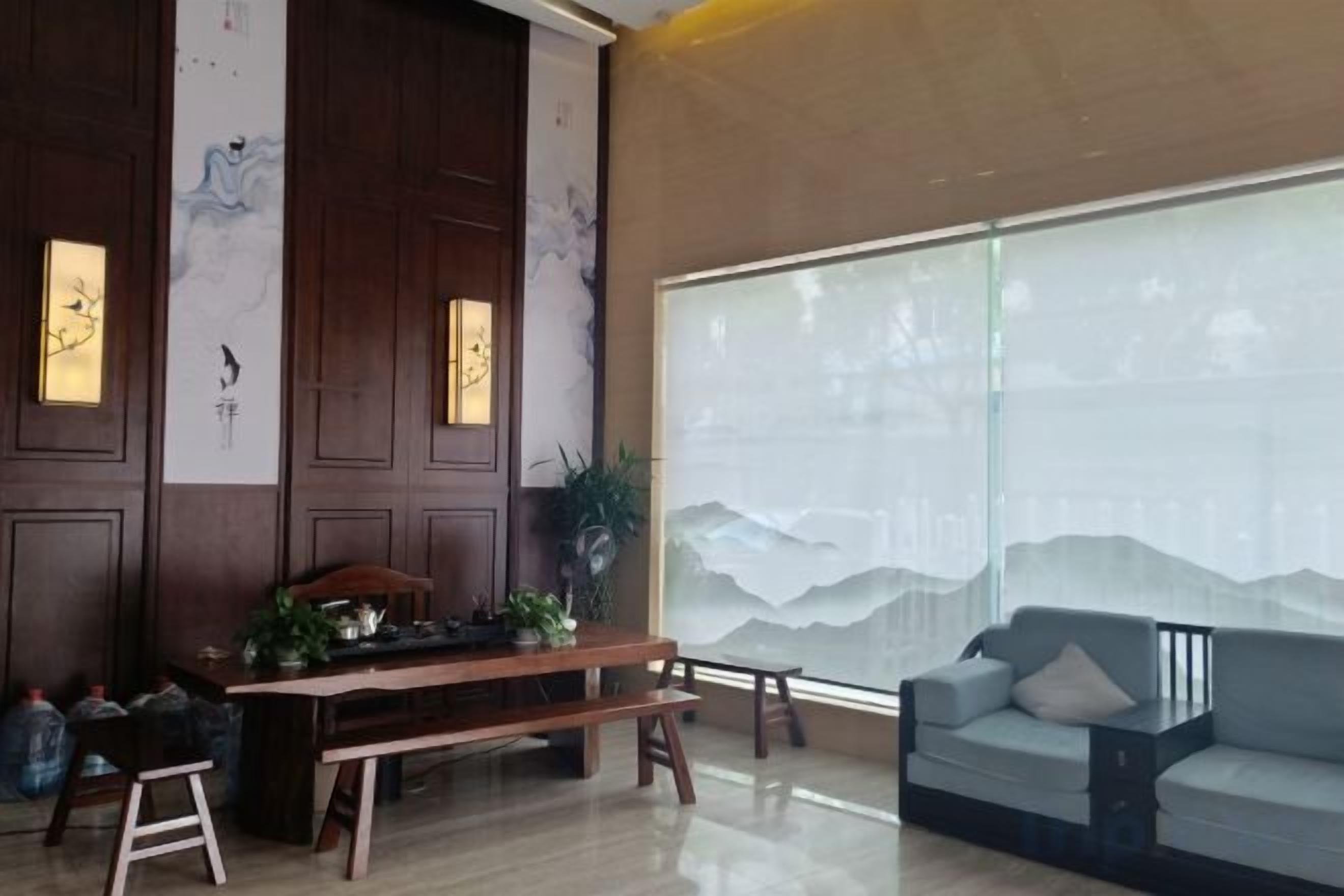 A room with a wooden table, a sofa, and a large window with a view.