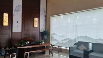 A room with a wooden table, a sofa, and a large window with a view.