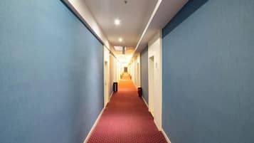 A corridor with blue walls and a red carpet, leading to a door at the end.