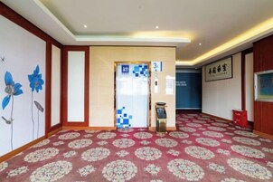 Un vestíbulo de hotel con alfombra estampada, una recepción y una pared con un mural floral.