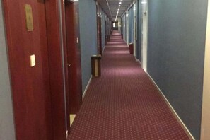 A hotel corridor with doors on the left, a carpeted floor, and a blue wall on the right. - Linhai H Chain Lihao Star Hotel (Linhai)