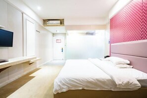 Una habitación de hotel moderna con una cama, un televisor y un escritorio.