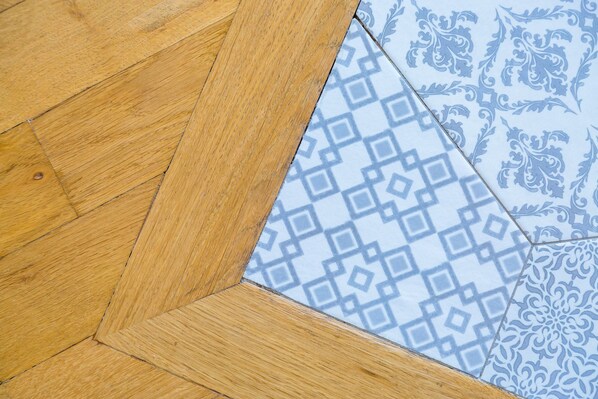 A corner of a wooden floor meeting a patterned tile. - Chiaia Mon Amour Elegant Flat by Napoliapartments (Naples)