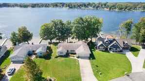 Zona residencial con casas cerca de un lago, con césped bien cuidado y entrada para vehículos.