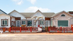 A row of white buildings with red railings and a large garage door. - Sokcho Seohyeon Ine Pension (Sokcho)