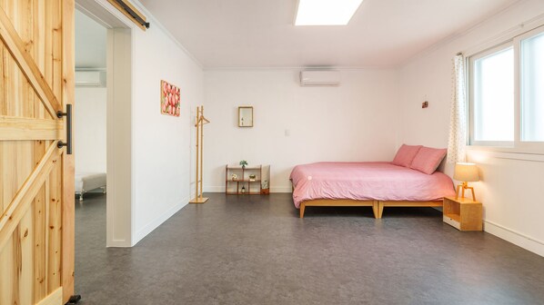 A bedroom with a bed, a bedside table with a lamp, a wardrobe, a mirror, and a shelf with plants.