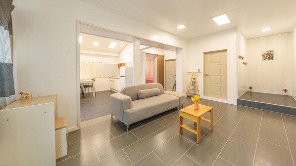 A modern living room with a sofa, a small wooden table, and a kitchen in the background. - Sokcho Seohyeon Ine Pension (Sokcho)