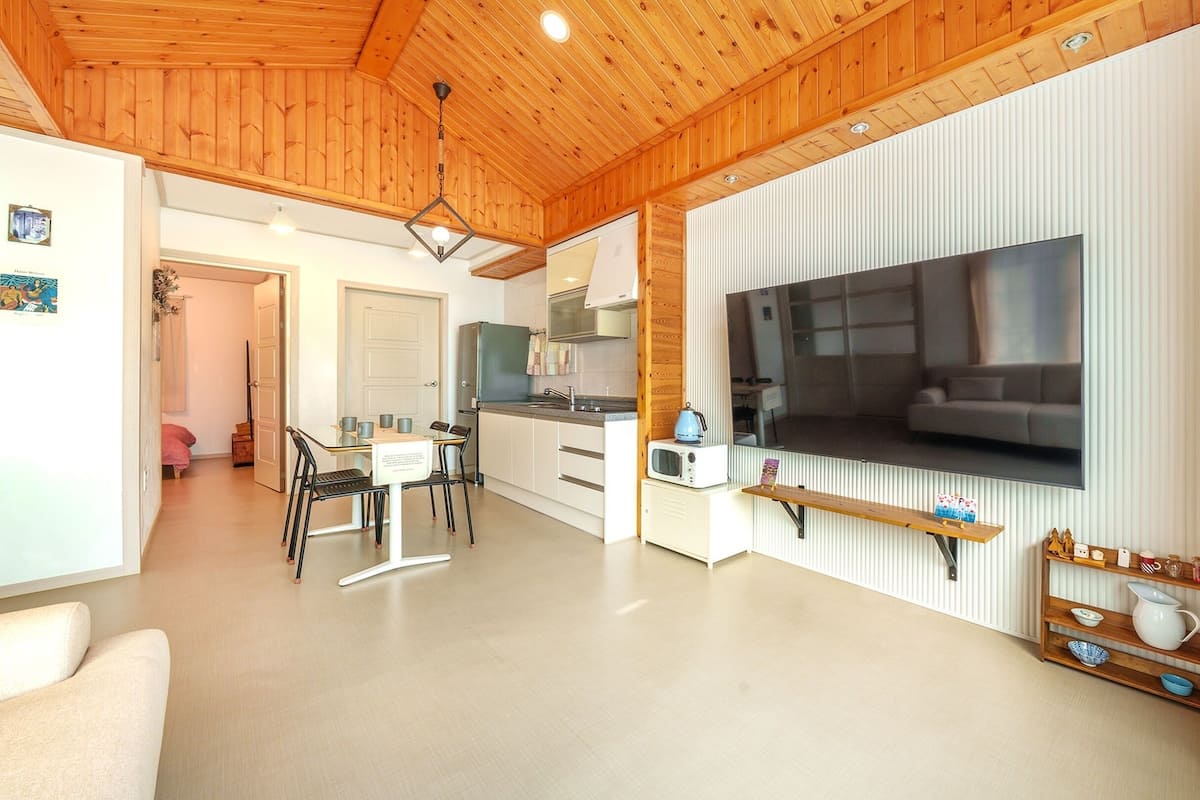 A compact living space with a kitchen, dining area, and a TV mounted on the wall.