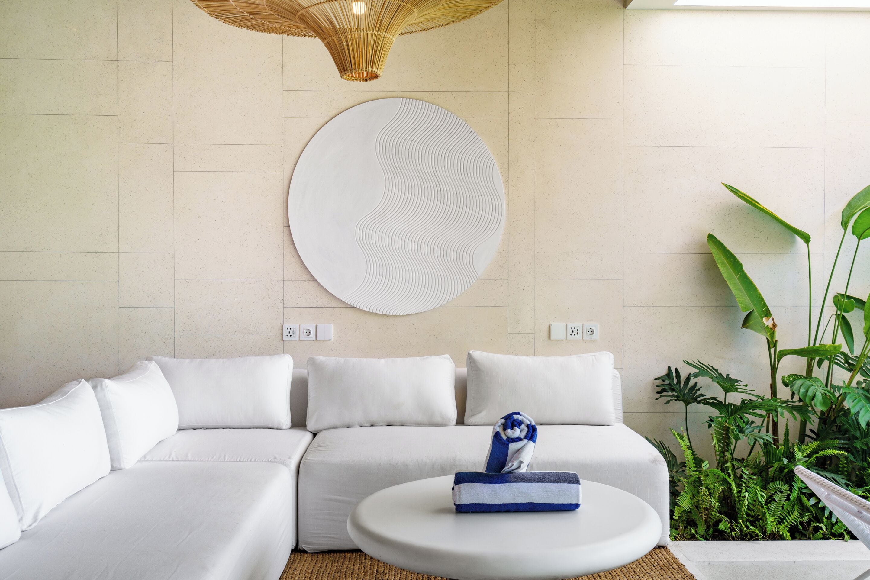 Una sala de estar moderna con un sofá seccional, una mesa de centro redonda y una gran obra de arte en la pared.