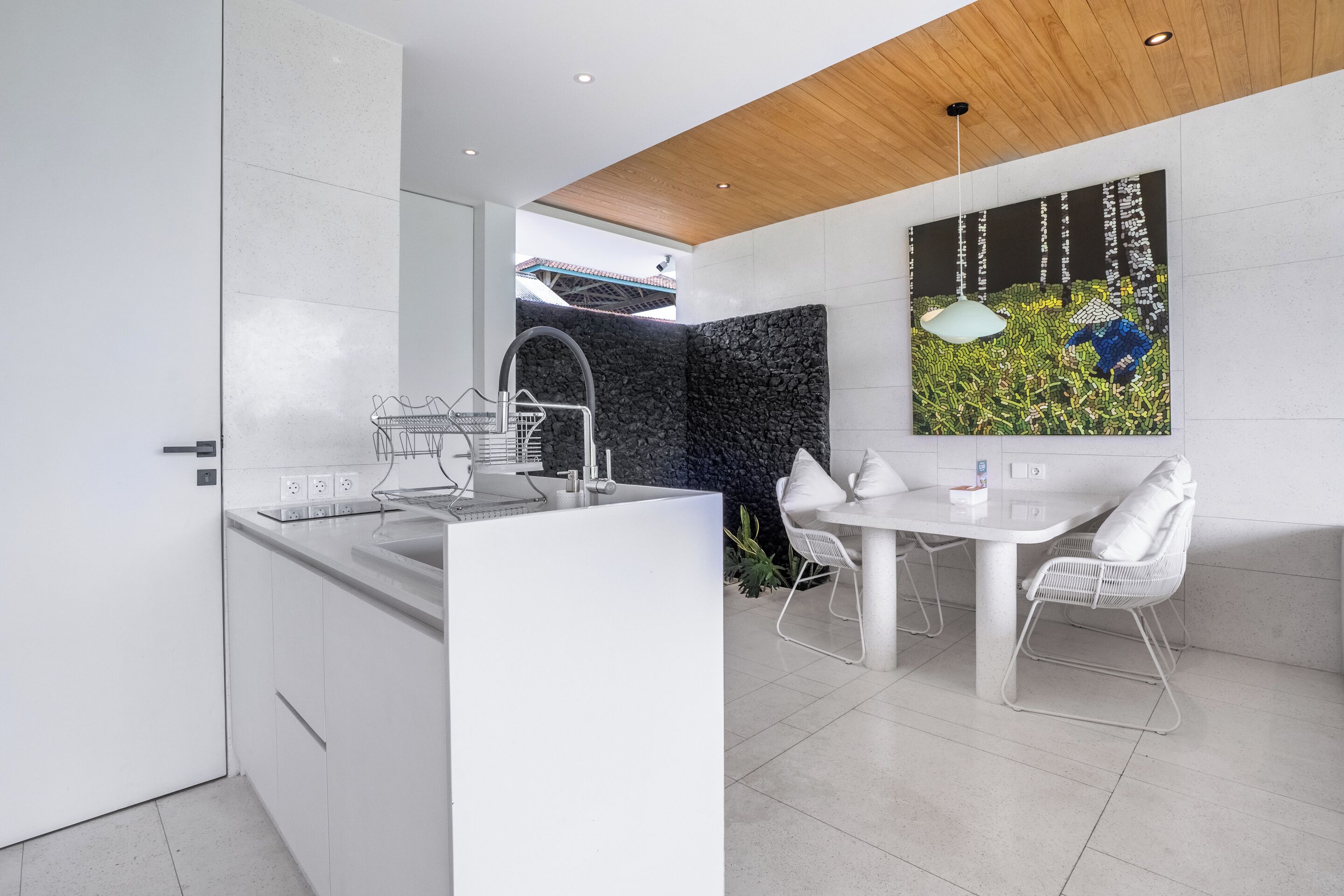 A modern kitchen with white cabinetry, a central island, and a dining area with a white table and chairs.