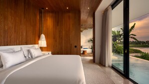 Quarto de hotel moderno com uma cama grande, painéis de madeira, vista para uma piscina e uma área de refeições ao fundo.