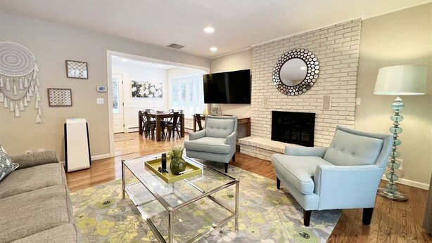Una sala de estar con chimenea, dos sillones, una mesa de centro y un televisor montado en la pared.