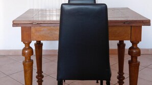 Una mesa de comedor de madera con cuatro sillas, una de ellas negra.
