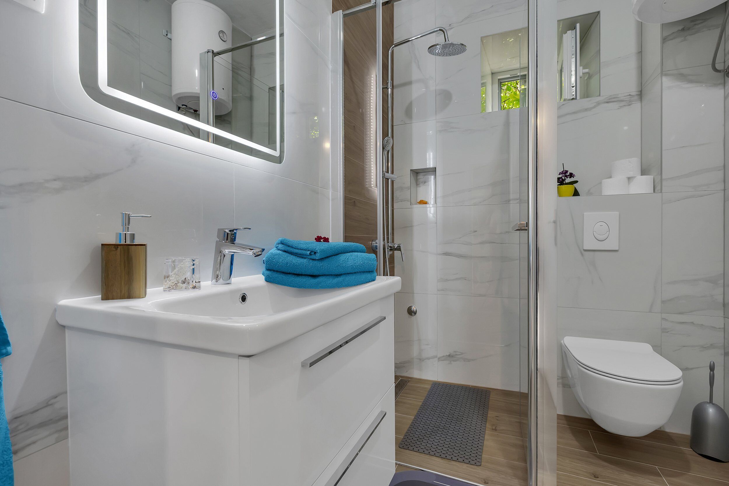 A modern bathroom with a white sink, mirror, and toilet.