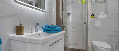 A modern bathroom with a white sink, mirror, and toilet.