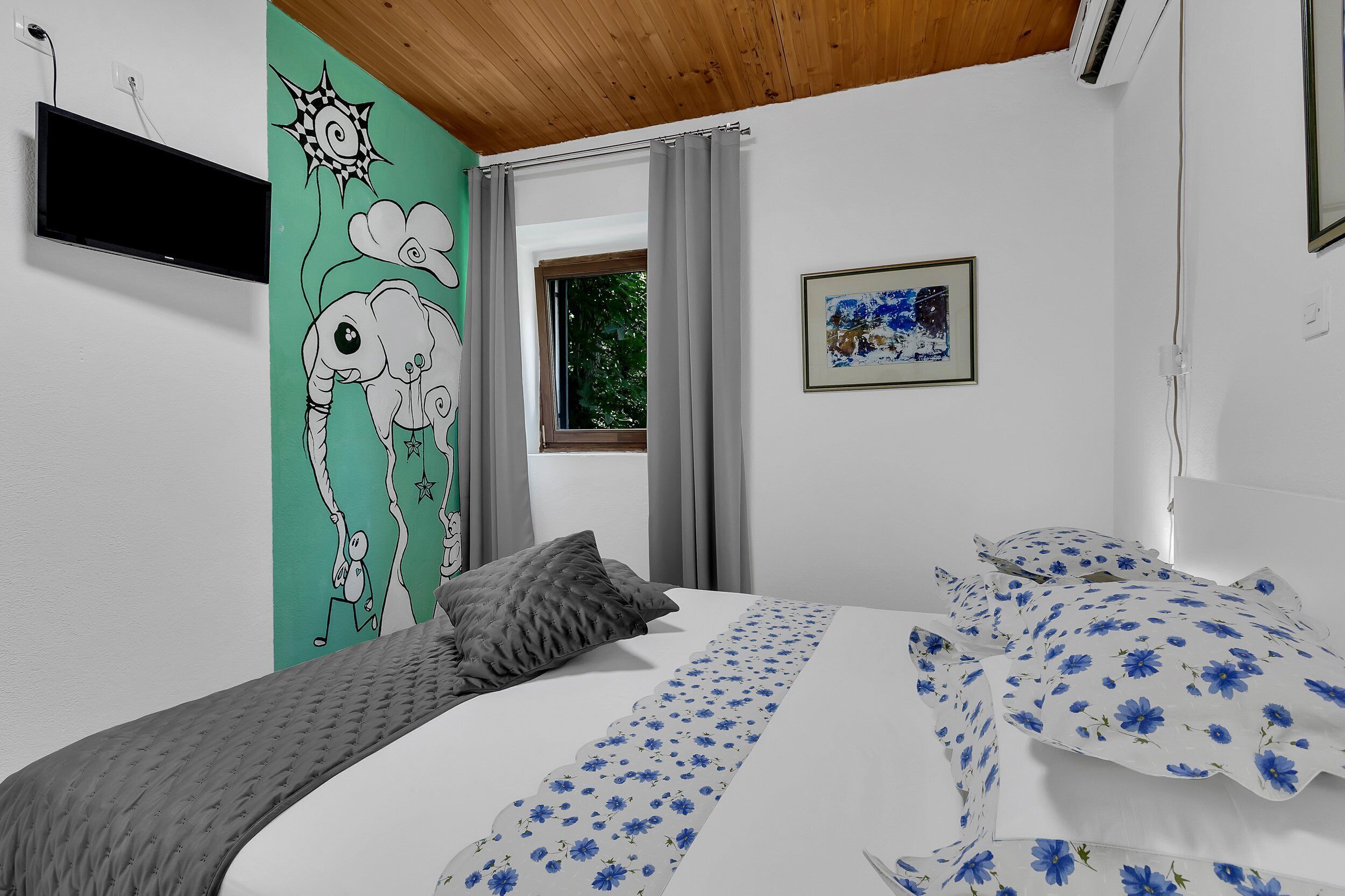 Una camera da letto con un letto, un affresco, una finestra e un quadro incorniciato.