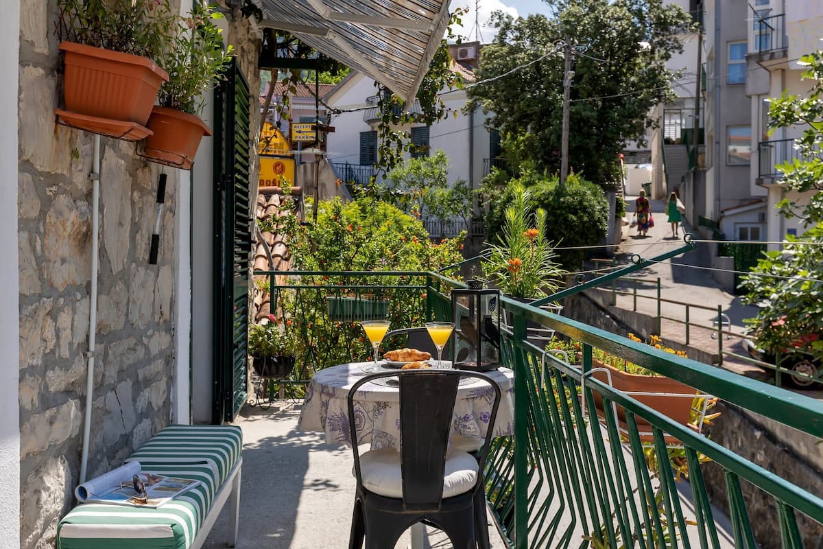 Un balcon avec une table, des chaises et des plantes en pot.