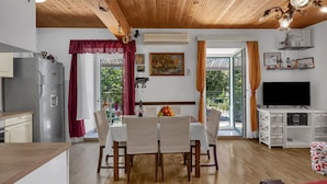 A modern kitchen with a refrigerator, dining table with chairs, and a TV. - Apartments Kata (Makarska)