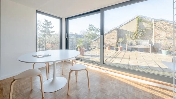 A modern room with a large window, a round table, and four chairs. - Peaceful 2 Bedroom Flat With Roof Terrace - Hackney (London)