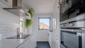 A modern kitchen with white cabinetry, a black countertop, and stainless steel appliances including an oven and a microwave. - Peaceful 2 Bedroom Flat With Roof Terrace - Hackney (London)