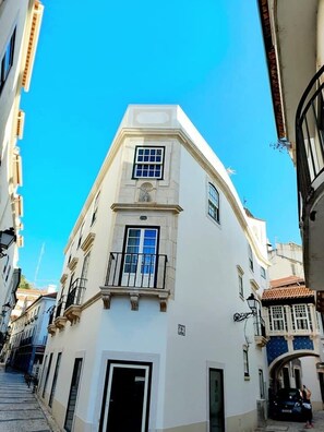 A narrow street with a white building featuring a balcony and a small window. - Beautiful Family Apartment in Leiria (Leiria)