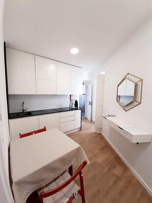 A modern kitchen with white cabinets, a black countertop, and a red chair. - Beautiful Family Apartment in Leiria (Leiria)