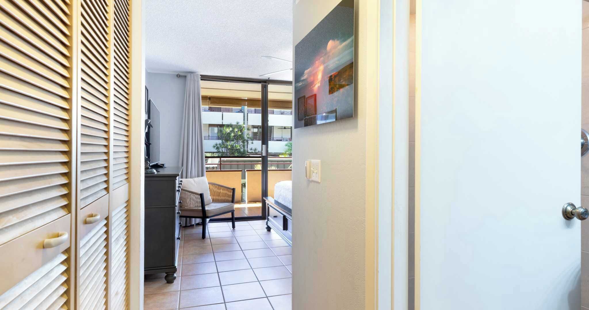 Een hotelkamer met balkon, bureau en bed.