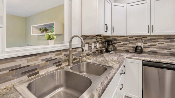 A modern kitchen with white cabinets, a double sink, and a built-in dishwasher. - Abby's Place - Close to Attractions (Branson)