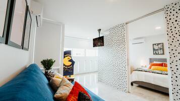 A modern hotel room with a large bed, a blue sofa, and a patterned wall.