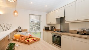 Eine moderne Küche mit weißen Schränken, einer Holzausziehtheke, einem Gasherd, einer Mikrowelle und einem Toaster.