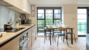 A modern kitchen with a dining area, large windows, and a view of the outside. - Greenwich Perfection (London)