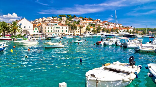 A marina with boats docked, clear turquoise water, and a backdrop of colorful buildings. - Apartment 11 Sleeps 4 Guests (Split)