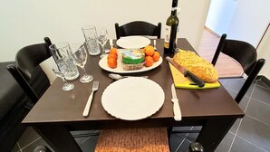 A dining table set with plates, cutlery, glasses, a bottle of wine, and food items. - Apartment 11 Sleeps 4 Guests (Split)