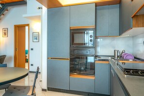 A compact kitchen with grey cabinets, a built-in oven, a microwave, and a sink.