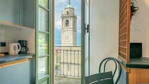 Un balcone con vista su una torre, una sedia, un tavolo e una macchina per il caffè.