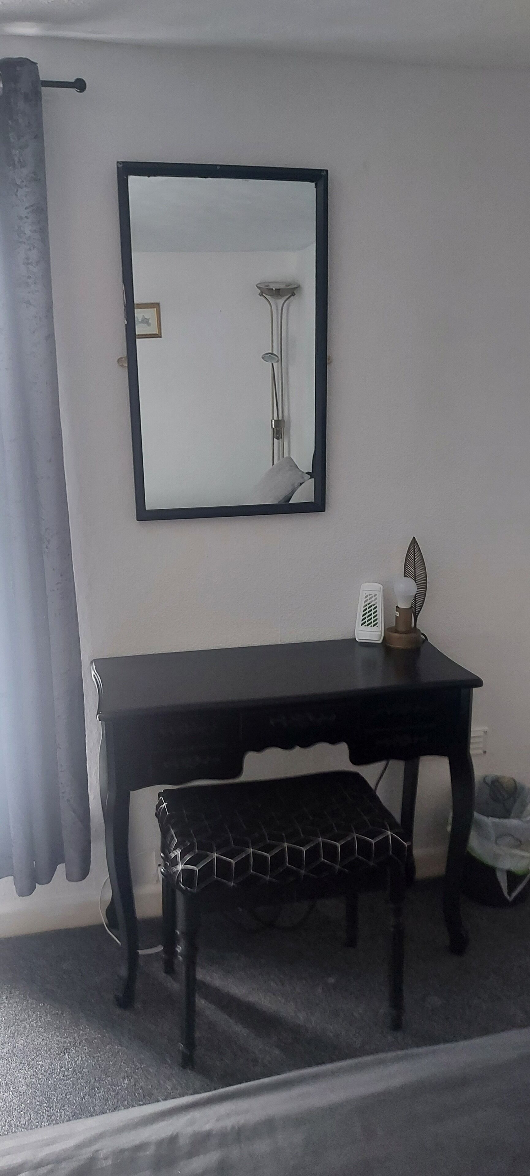 Een kamer met een zwarte tafel, een bankje, een spiegel en een wit object op de tafel.