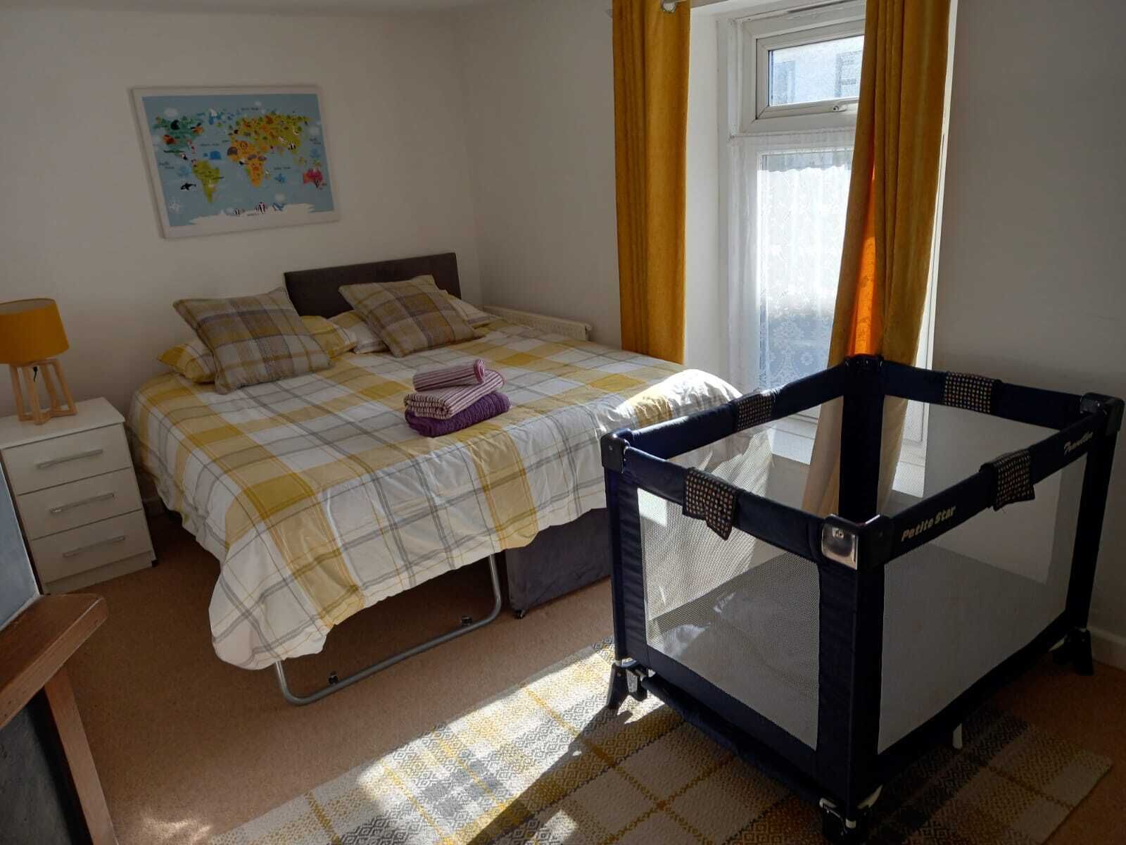A bedroom with a bed, a nightstand, a map on the wall, and a crib.