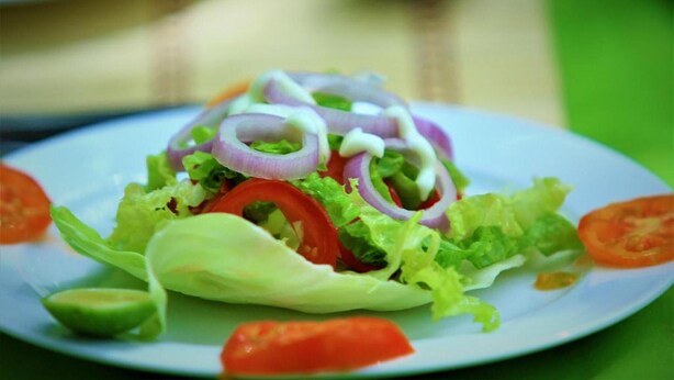 A plate of salad with lettuce, tomatoes, and red onions.
